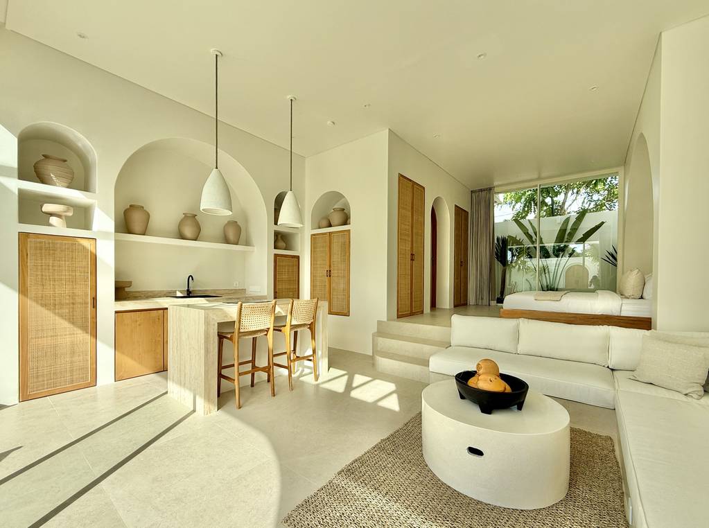 Modern tropical living space with minimalist design, neutral tones, natural materials, and lush greenery views.