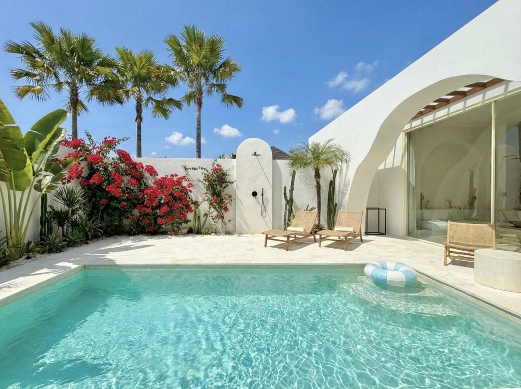 Bright, modern poolside retreat with lush greenery and vibrant flowers in Bali.